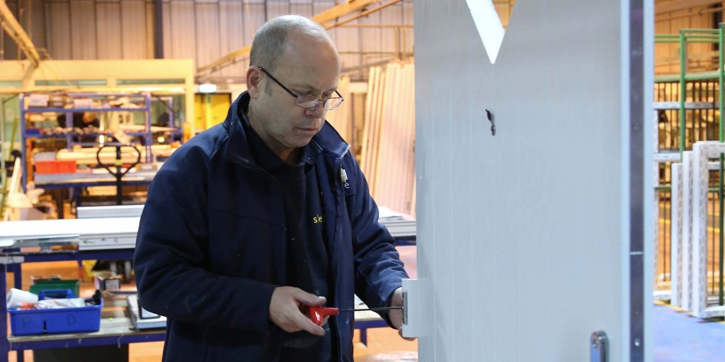 A skilled engineer working on finishing a composite door ready for installation