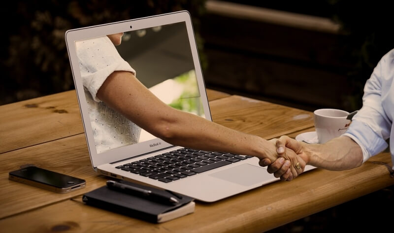 Laptop with arm coming out and shaking hands